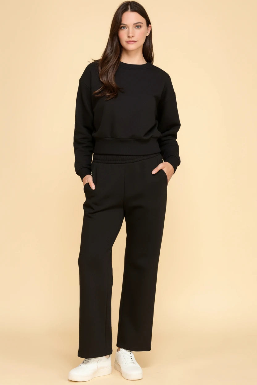 Women modeling a black long-sleeve sweatshirt with matching straight-leg lounge pants and side pockets.