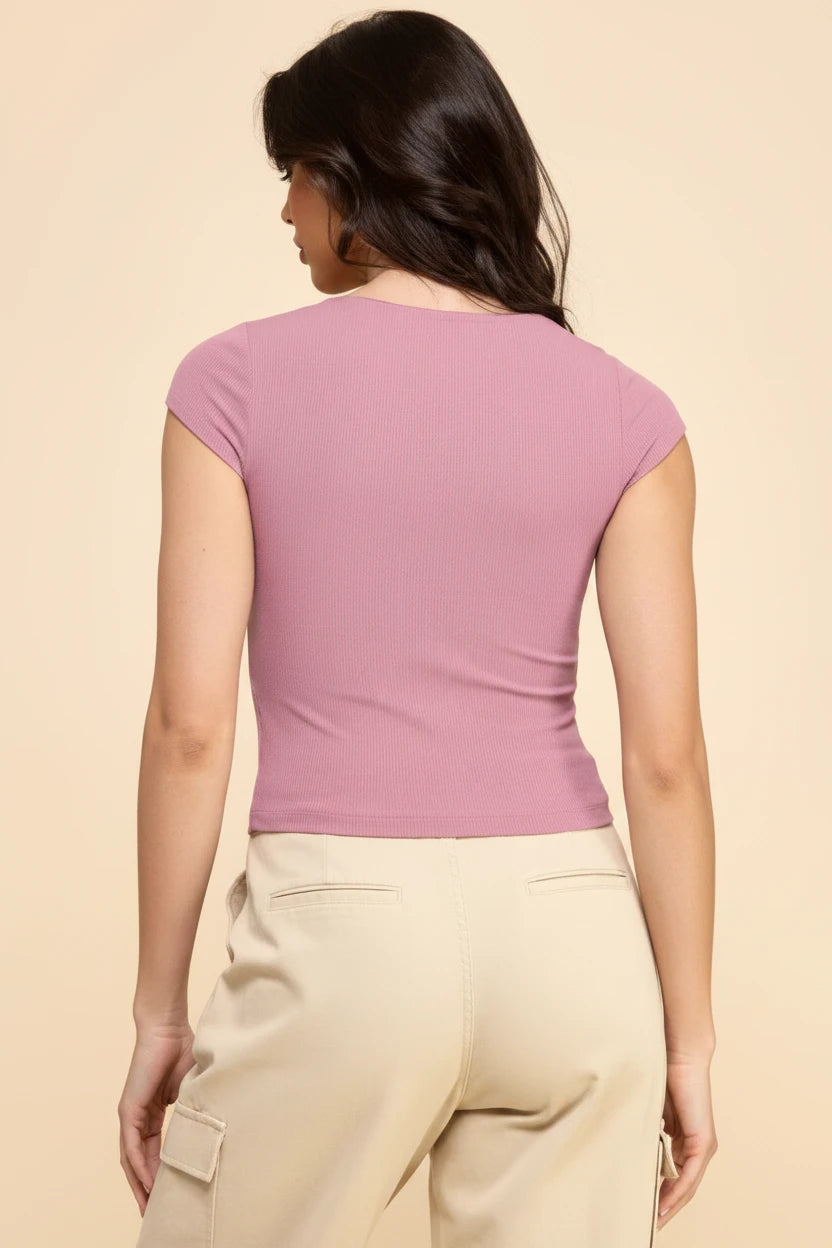 Woman wearing a pink top and beige pants on a beige background