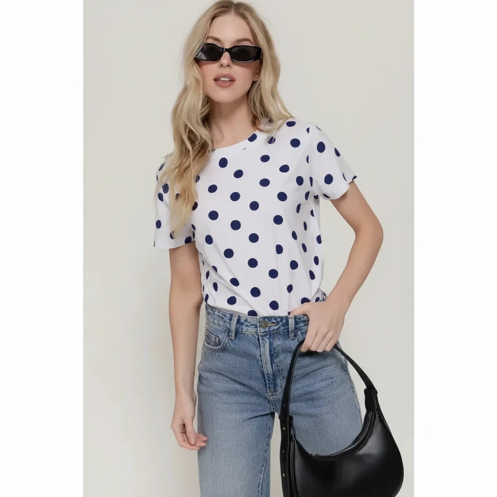 Model wearing the Dottie white short-sleeve top with black polka dots, styled with blue jeans.