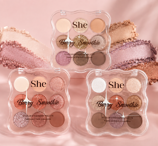 Three clear clamshell eyeshadow palettes labeled 'She Berry Smoothie' arranged on a soft pink background with matching eyeshadow swatches behind them. The palettes contain multiple warm-toned shades including beige, pink, bronze, brown, and glitter finishes.