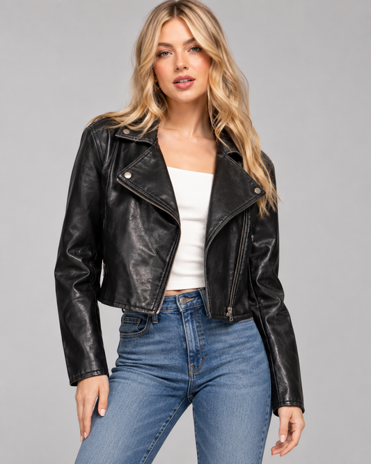 model wearing a black cropped faux leather moto jacket with an asymmetrical zipper, paired with a white top and blue jeans.