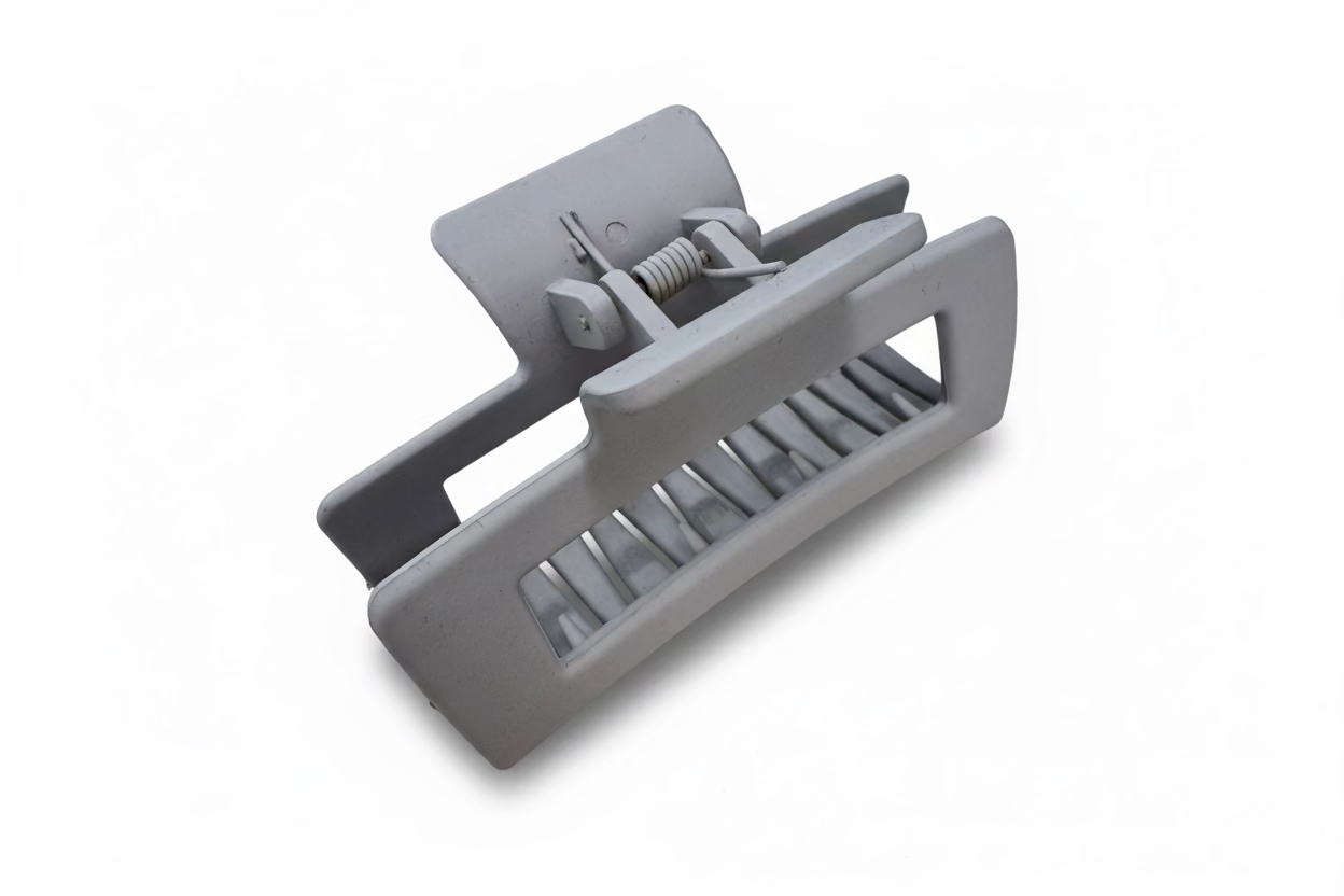 Gray plastic component on a light-colored surface with a laptop in the background