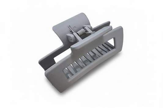 Gray plastic component on a light-colored surface with a laptop in the background