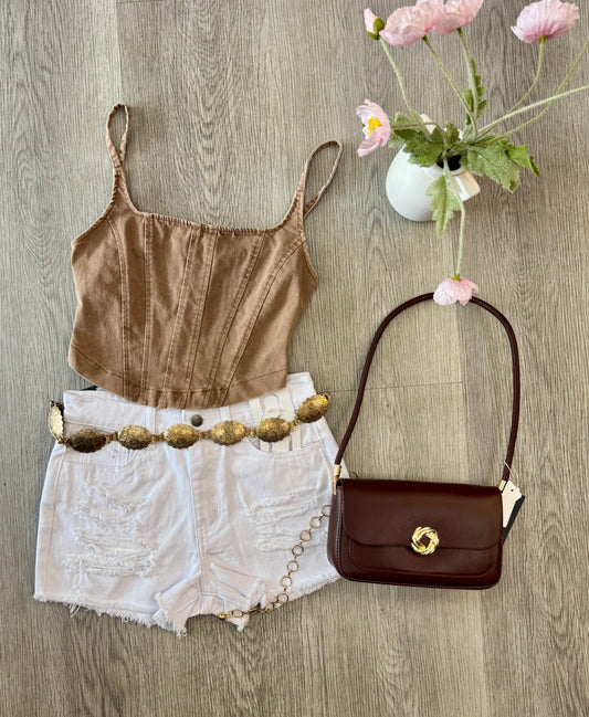 Brown stretchy denim corset tank top with thin straps styled with distressed white denim shorts, gold belt, and brown shoulder purse for a trendy chic boutique outfit.