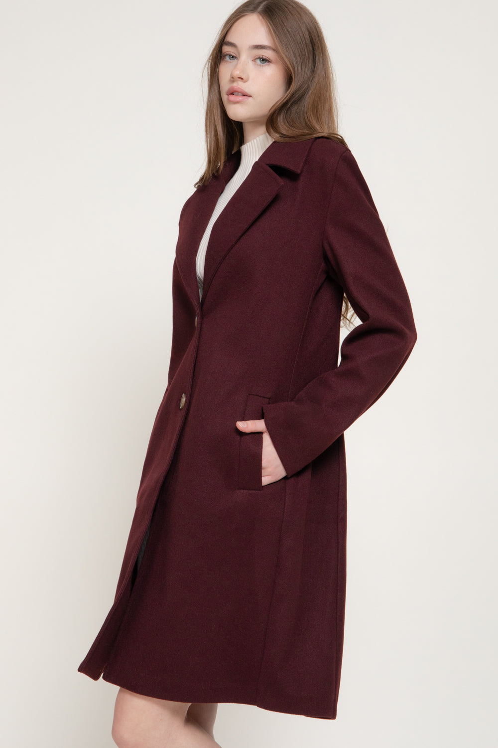 model wearing the Amelia burgundy a-line with a flattering long silhouette, classic buttons and front pocket detailing. 