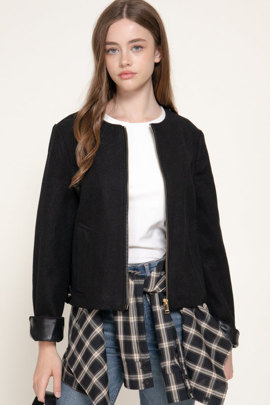 model wearing the black felt-style jacket with faux leather cuffs, paired with a white top.
