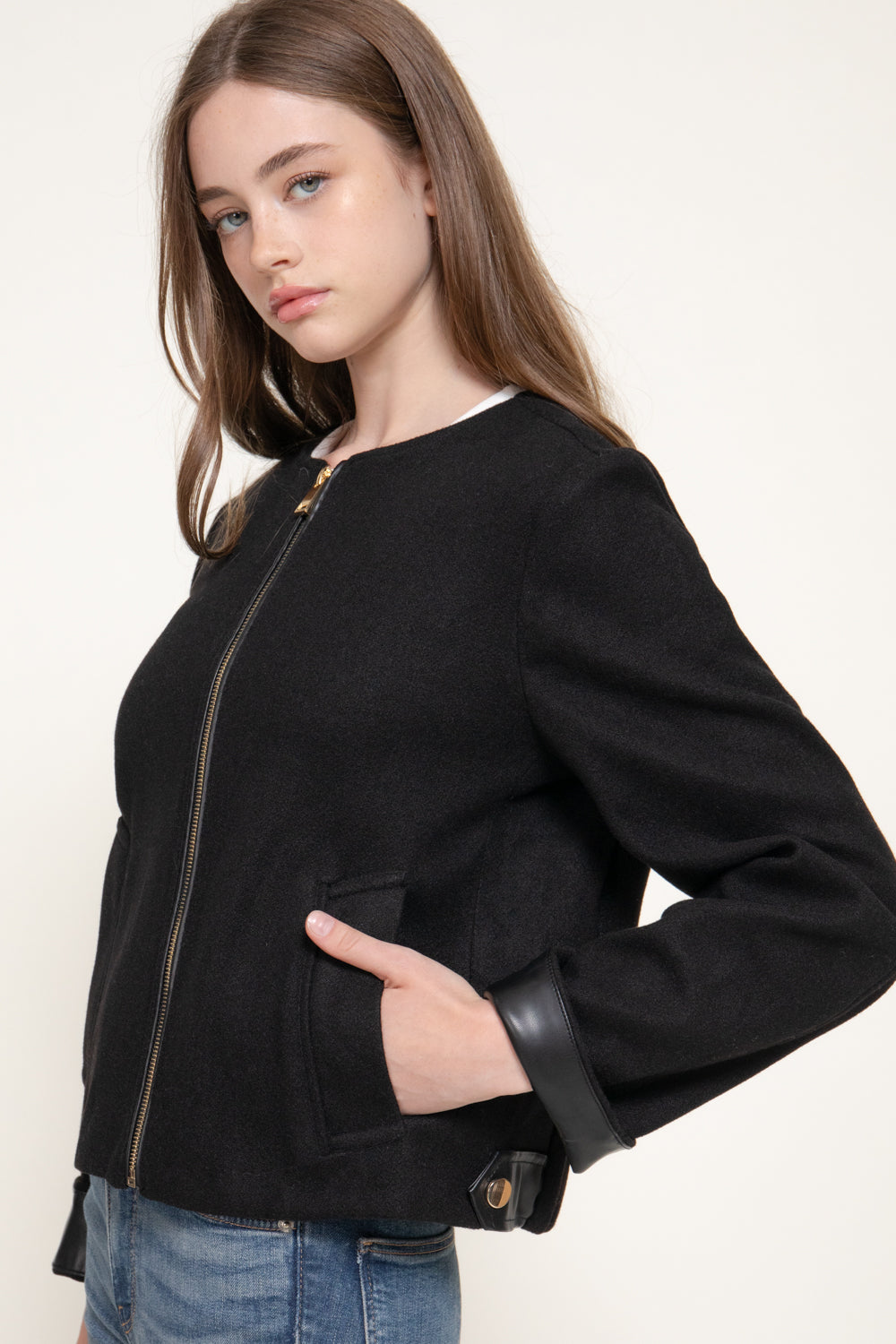 side view of the black jacket showing its relaxed fit and faux leather cuffs. 