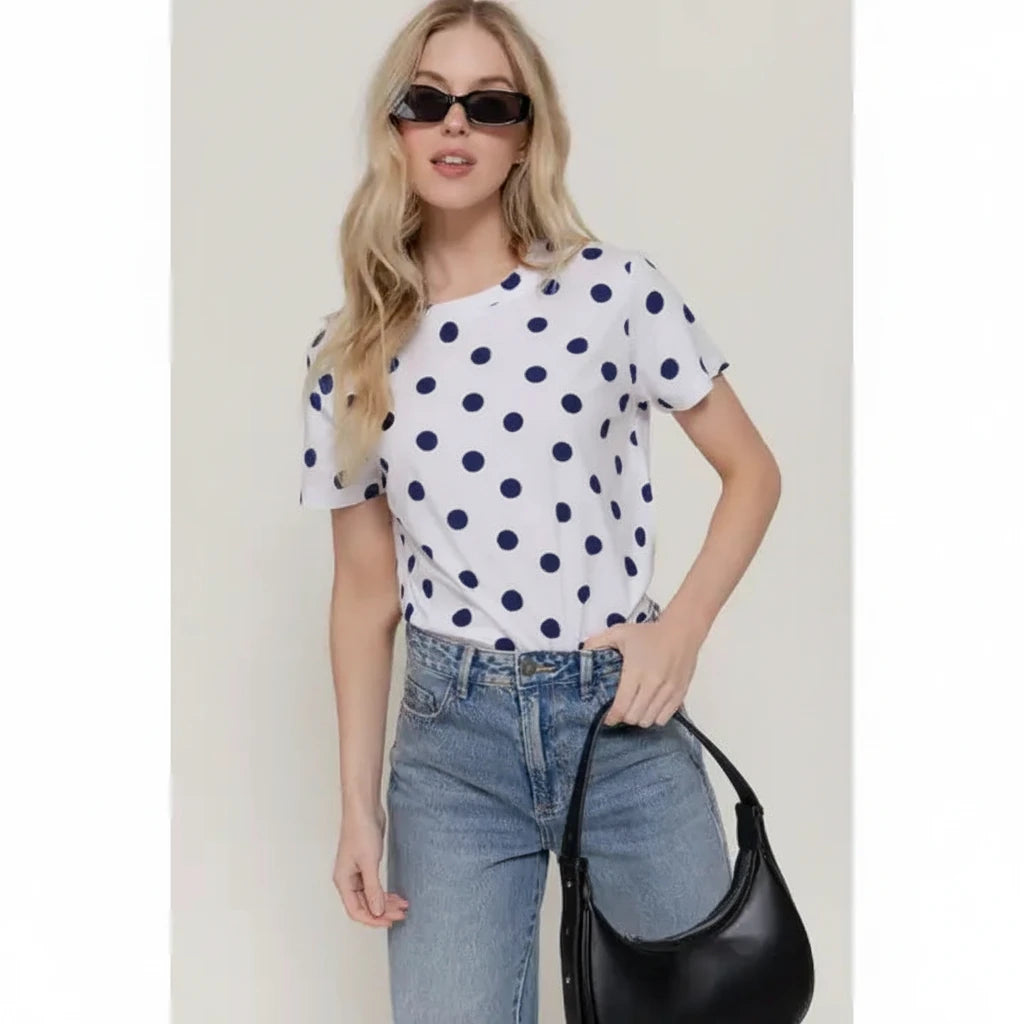 Model wearing the Dottie white short-sleeve top with black polka dots, styled with blue jeans.